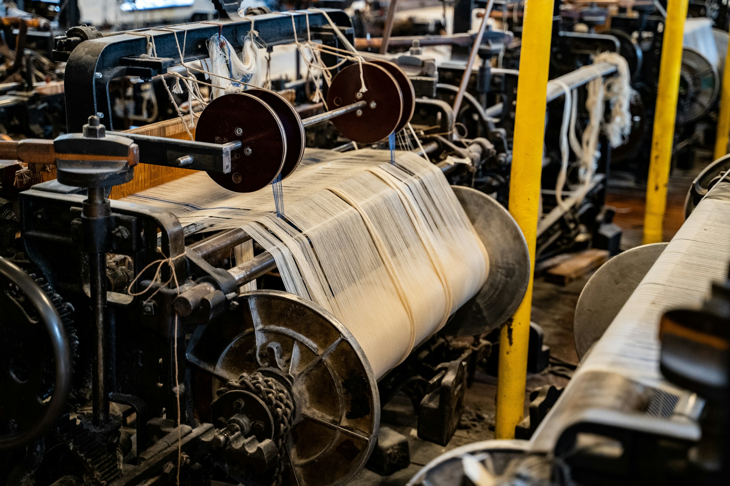 Textile mill weaving floor with industrial looms and yarn